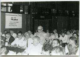 Mann spricht an einem Anlass, im Hintergrund Plakat "72 Jahren LFSA", 63. Delegiertenversammlung vom 25. Mai 1991, Hotel Nova-Park, Zürich