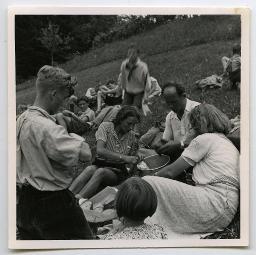 Georges Kutter und zwei Betreuerinnen sitzen um eine Pfanne bereiten das Essen zu; daneben sitzen und stehen Kinder; 1941