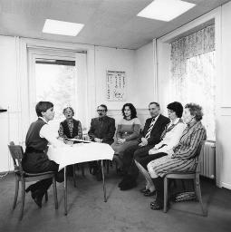 "Unterricht des Schwerhörigen-Vereins Zürich" - Gigi Ménard sitzt an einem Tisch, Fr. Guber, Li. Morath, unbekannt, Hr. Spillmann, Vreni Schneider und Fr. Dolder (v.l.n.r.) sitzen auf Stühlen im Halbkreis ihr gegenüber und sprechen ihr nach; um 1990