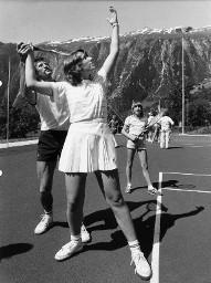 Tennisplatz im Freien - Tennislehrer einem Mädchen den Aufschlag (Service) zeigend und ein Mädchen zusehend, Blatten, 1983