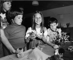 Vier Kinder basteln mit Wolle (Figuren aus Bommeln)