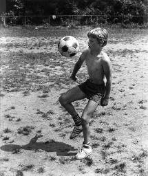 Knaben mit nacktem Oberkörper mit einem Fussball im Freien übend (Ballübungen), Sonvico 1978