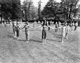 Kinder stehen auf der Wiese (Fussballplatz) und bilden mehrere Kreise, Magliaso 1978
