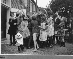 Znüni - Knaben und Mädchen sammlen sich um eine Person herum, welche das "Znüni" austeilen will und welche nicht sichtbar ist (zwischen den Kindern versteckt)