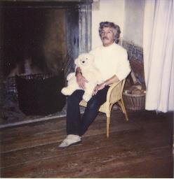 Bob Steffen, graumeliert und Schnauz; auf Rattanstuhl mit Teddybär vor Kamin, um 1985
