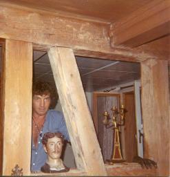Bob Steffen mit Büste; guckt durch Holzpfosten; in Bauernhaus, 1973