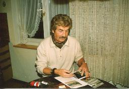 Bob Steffen, Haare getönt, Schnauz; sortiert Fotos an Tisch, um 1985