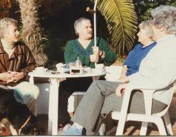 Bob Steffen (links), graumeliert, mit Schnauz, mit Freunden am Tisch unter Palmen, um 1995