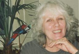 Eliane Staro stützt Kinn auf der Hand ab; im Hintergrund farbiger Holz-Papagei, 1998