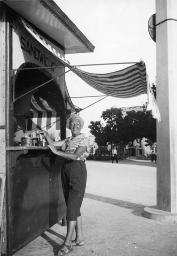 Unbekannte ältere Frau in gestreifter Bluse und Caprihose an Standbar, um 1950