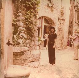Junge Frau in Schwarz steht vor malerischer Strassenecke, um 1970