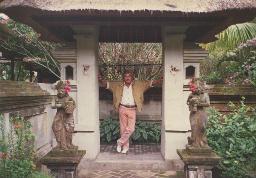 Bob Steffen, graumeliert mit Schnauz, Freizeitlook mit rosa Hose, steht an Torkonstruktion, asiatische Gottheiten