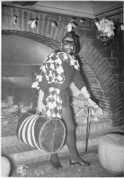 Bob Steffen kostümiert als Zorro mit gestreiftem Koffer und Gehstock vor Kamin, um 1955