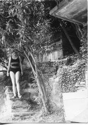 Thea Kuiper im Badeanzug auf Treppe vor verwildertem Haus, 1966