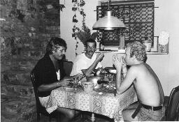 Bob Steffen (links) mit Schnauz zu Tisch mit zwei unbekannten Männern, um 1975