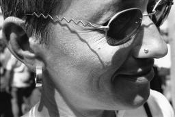 Nahaufnahme Frauengesicht, Frau trägt Sonnenbrille, silberne Ohrringe und Nasenpiercing; Christopher Street Day 1998 in Bern