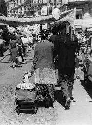 Verkleidete Frau mit Ziehwagen mit Aufschrift "Lesbe" mit verkleidetem Mann an ihrer Seite während einer Demonstration; wahrscheinlich Hetero Garanti(e) 04.08.1981
