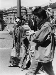 Verkleidete Frau mit langem Rock und diversen Schälen, Sonnenbrille und Papiermaske im Gesicht , zweite Frau studiert ein Papier, laufend; wahrscheinlich Hetero Garanti(e) 04.08.1981