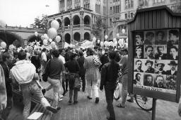Demonstranten mit weissen Ballonen bei Urania (Zürich), im Vordergrund Anzeigetafel zu Ausstellung im Stadthaus Zürich; Demonstration 24.06.1989 zu 20 Jahre Stonewall während der Aktion "20 Tage lesbisch-schwule Kultur" 09.06 - 01.07.1989 in Zürich