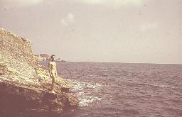 Bob Steffen nackt am Meer auf Felsen stehend schaut in Kamera, Serie, um 1950
