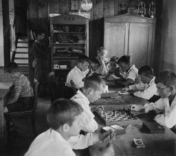 ...und ein Regentag vereint die ganze grosse Familie im Spielsaal - Kinder spielen Schach und ein Kartenspiel - Bücherregal mit der Beschriftung "FKZ", Kolonie Weisslingen