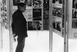 Mann Plakate einer Ausstellung (vermutlich) zuschauend - Kleinplakate mit der Beschriftung: "1. Mai Alle vereint, ...denn alle Arbeiter sind Fremdarbeiter" (Kongress 1978)
