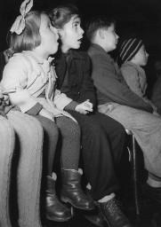 Grossaufnahme von vier zuhörenden Kindern (vermutlich Treffen/Anlass der Gewerkschaft) in einem Saal