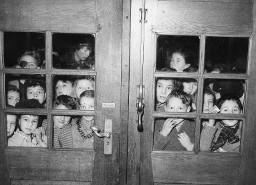 Gruppe von Kindern hinten den Türglasscheiben eines Gebäudes wartend (vermutlich Treffen/Anlass der Gewerkschaft)