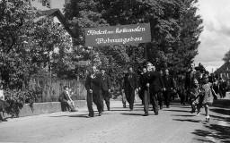 Gruppe von Personen demonstrierend - Schild mit der Beschriftung: "Fördert den kommunalen Wohnungsbau"