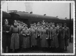 Album Alfred Brauchli, Teil 3/3, Ärzte- und Pflegermission des Schweizerischen Roten Kreuzes an der Ostfront, Winter 1942/1943: Gruppenfoto mit Leuten in Mäntel (vermutlich der Schweizer Armee) und mit Schweizerkreuz gekennzeichneten Feldmützen neben Männern in Uniform der Wehrmacht des Deutschen Reiches, "Ankunft in Berlin"