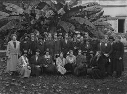 Gruppenporträt, Frauen auf einer Wiese, vor einem Haus und Bananenbäumen, um 1920