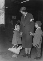 Eine Frau von der Bahnhhilfe Freundinnen junger Mädchen mit zwei Kindern an der Hand, am Bahnhof stehend, um 1950
