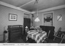 "Bahnhofstübli" Zimmer mit Tisch, drei Stühlen, Sofa, Kommode und Schirmständer, 5. Juli 1928
