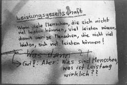 Spruch an einer Mauer: "Leistungsgesellschaft  Wenn viele Menschen, die sich nicht viel leisten können, viel leisten müssen, damit wenige Menschen, die nicht viel leisten, sich viel leisten können!"