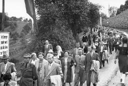 Plakat "Ist Energie mehr wert als die Liebe zur Heimat?" am Wegrand, davor Demonstrationsteilnehmer auf dem Weg zur Klosterinsel Rheinau anlässlich der Kundgebung der Rheinaubewegung am 31.08.1952
