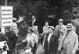 Eine Gruppe von Teilnehmer der Protestveranstaltung, vorbeigehend am Plakat "Kämpft für das Mitspracherecht des Volkes bei der Erteilung von Wasserrechts-Konzessionen", am Wegrand anlässlich der Kundgebung der Rheinaubewegung am 31.08.1952