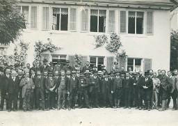 Gruppenbild von knapp 50 Männern, möglicherweise Forstleute, vor rebenumranktem Haus, ca. 1920