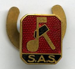 "S.A.S." – Anstecker mit Emblem des Schweizerischen Arbeitersänger-Verbands (SAS),  Musiknote und Hammer, goldfarben auf rotem Grund, darunter das Kürzel auf schwarz. Rückseitig mit hufeisenförmiger Klammer zur Befestigung, ca. 1940