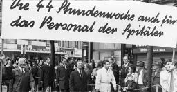 "Die 44 Stundenwoche auch für das Personal der Spitäler": Kundgebungsteilnehmer mit Transparent an 1.Mai-Kundgebung, um ca. 1980