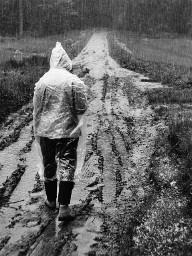 "Platzregen", Person mit Regenschutz im Schlamm laufend