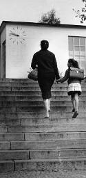 "Schulanfang -  1. Schultag", Kind mit Mutter eine Treppe zur Schule hochgehend
