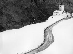 Verschneite Landschaft mit Strasse zu einer Kirche führend