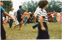 "Volkstanz auf dem Gelände Thielle am Neuenburgersee" - Junge Menschen und Kinder halten sich an den Händen und tanzen im Kreis, um 1982