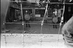 "AJZ-Schliessung" - Polizeieinsatz aufgrund der Räumung des autonomen Jugendzentrums / Blick durch den Maschendrahtzaun auf zwei Polizeibeamte, 04.09.1980
