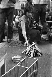 "Wohnungsdemo Werdplatz" - Einige Jugendliche, die sich auf dem Platz unterhalten; eine Frau zündet ein paar Holzscheite an, 01.10.1980