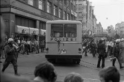 "Demo Bahnhofstrasse" - Grosser Polizeibus und zahlreiche Polizeibeamte kämpfen sich durch die stark belebte Strasse,ein Polizist gibt Anweisungen durch ein Megafon, Passanten beobachten das Geschehen, 04.10.1980