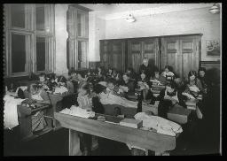 "Nähkurs Winterthur", Mädchen in Schulbänken während eines Nähkurses am nähen, um 1925
