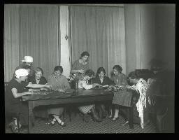 "Servicetöchterfürsorge", junge Frauen, versammelt an einem Tisch, spielend und nähend, um 1925