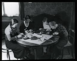 "Zürich, Töchterheim", vier Pensionärinnen sitzen gemeinsam an einem Tisch im Heim und stellen diverse Kleidungsstücke und Accessoires her, wie etwa Schuhe oder Handtaschen, um 1930