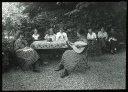 "Töchterheim Sihlwartheim, Zürich", Acht junge Frauen im Garten der Töchterheim, auf Stühlen oder einer Bank sitzend, einige am lesen oder stricken, eine spielt Mandoline, um 1930
